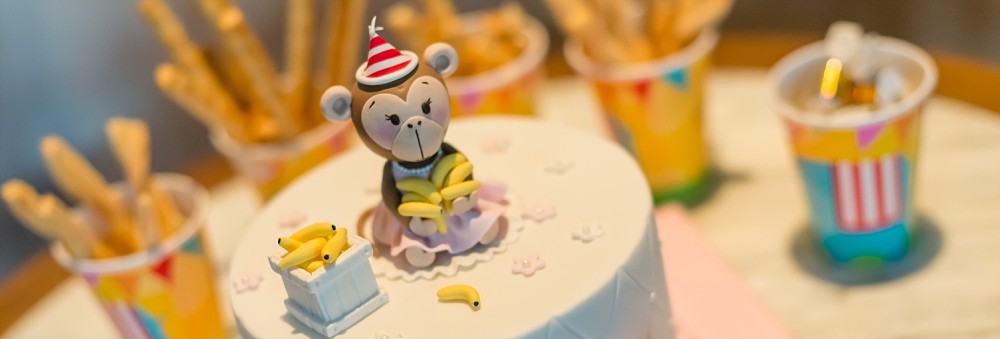 Birthday cake with monkey figure and party cups