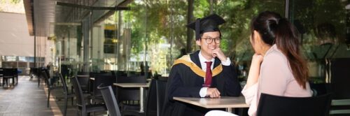 Young Asian couple at UNSW Tyree building in graduation gown