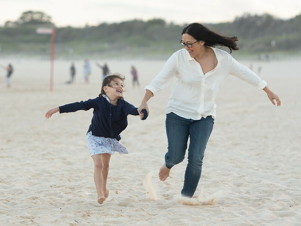 Mum running on beach with daughter