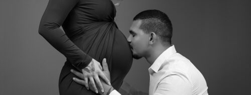 Pregnant belly in dress and man kissing belly