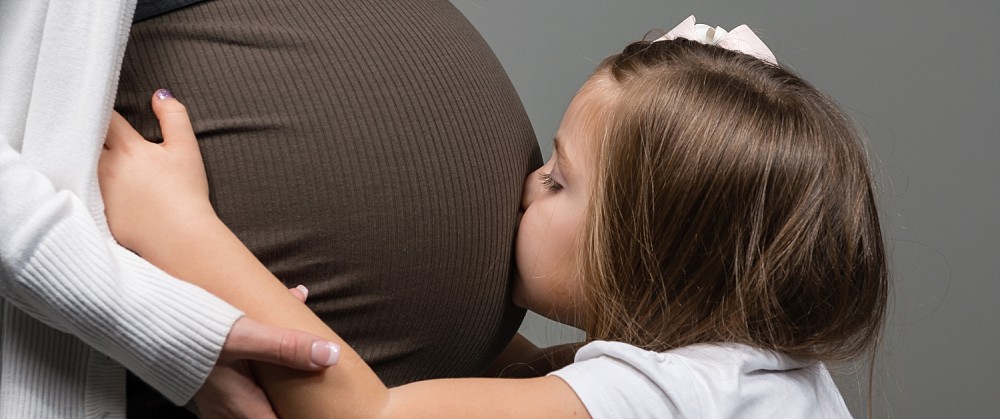 Blonde girl kissing pregnant tummy in studio photography in Coogee Sydney