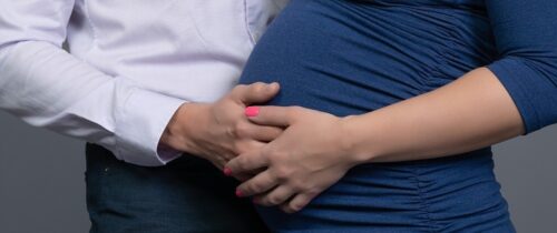Man and woman hands over pregnant tummy